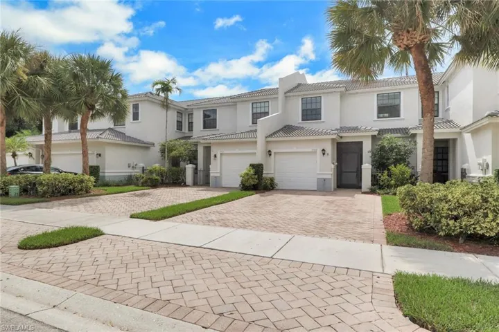 Multi-level exterior featuring light-toned stucco siding, a tiled roof, paver driveways, and integrated garage doors