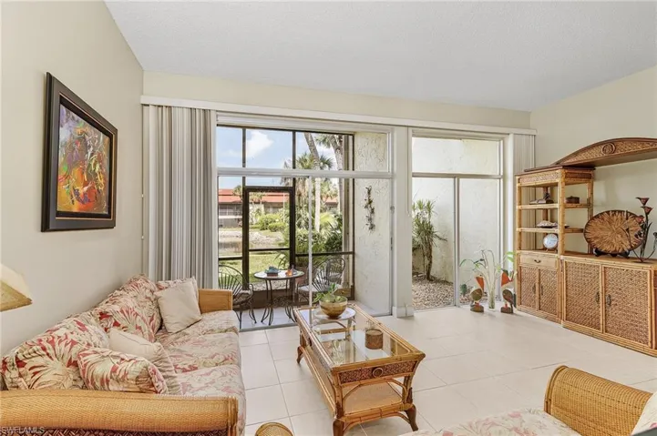 Living Room with screened lanai and access to WJ Village Pool - Staged. Furnishings in the photo are not in place. Replaced with like-minded couch, love seat, and armed sitting chair.