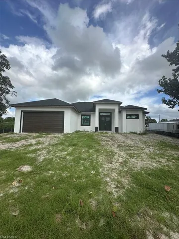 Prairie-style home with stucco siding, a garage, and driveway