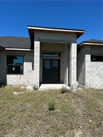 Entrance to property featuring a shingled roof, stucco siding, and french doors