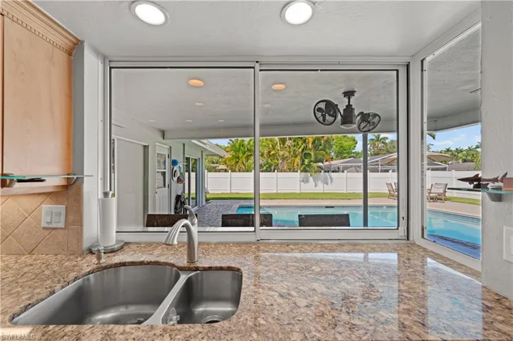 Kitchen featuring backsplash, sink, light brown cabinets, and stone countertops