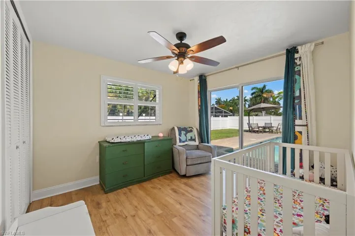 Bedroom with ceiling fan, a closet, multiple windows, and hardwood / wood-style floors