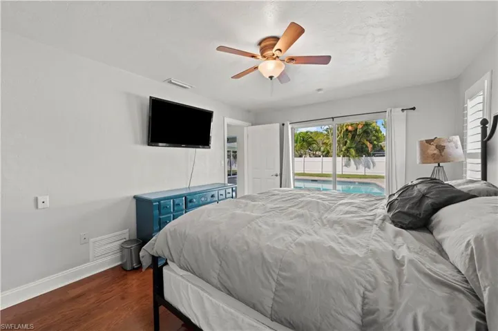 Bedroom with dark wood-type flooring, ceiling fan, and access to exterior