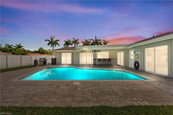 Pool at dusk featuring a patio