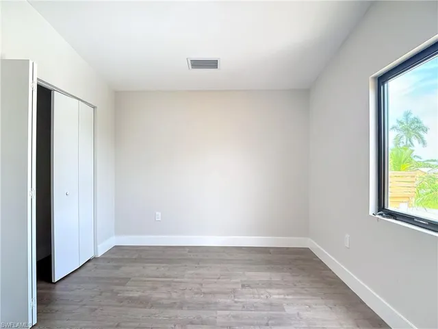 Unfurnished bedroom with wood finished floors, a closet, baseboards, and visible vents