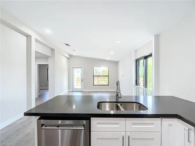 Kitchen featuring dishwasher, white cabinets, a sink, and a wealth of natural light