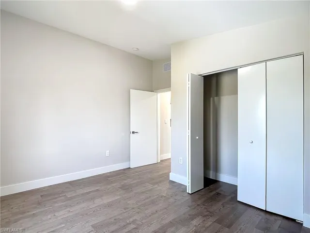 Unfurnished bedroom featuring visible vents, a closet, baseboards, and wood finished floors