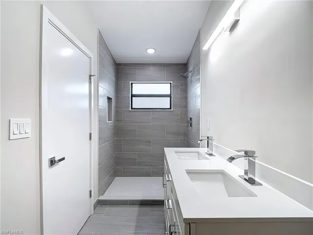Bathroom with double vanity, a sink, and a stall shower