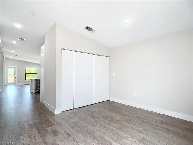 Unfurnished bedroom featuring baseboards, visible vents, vaulted ceiling, and wood finished floors