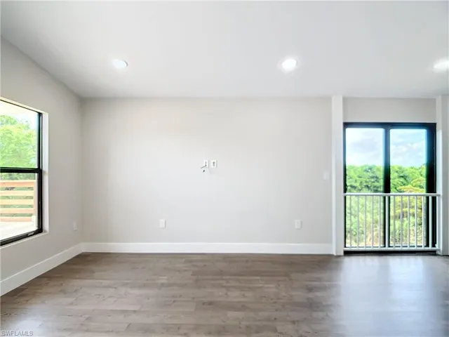 Empty room with baseboards, wood finished floors, and a healthy amount of sunlight