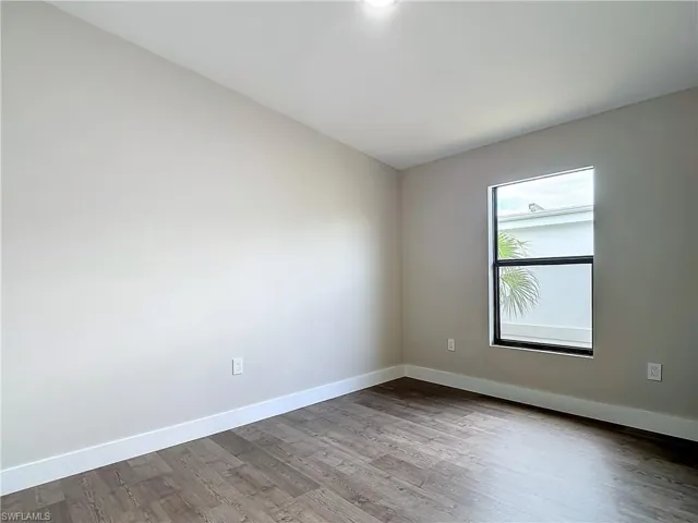 Unfurnished room with dark wood-type flooring and baseboards