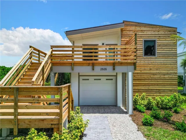 View of front facade featuring driveway, an attached garage, and stairway