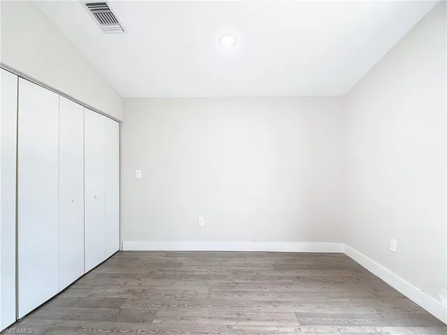 Unfurnished bedroom featuring a closet, baseboards, visible vents, and wood finished floors