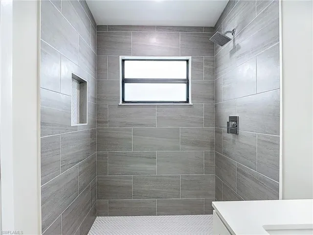 Full bath featuring vanity and tiled shower