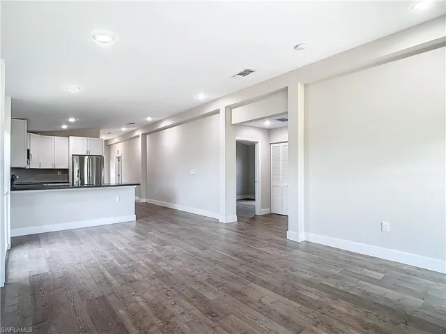 Unfurnished living room featuring wood finished floors, recessed lighting, baseboards, and visible vents