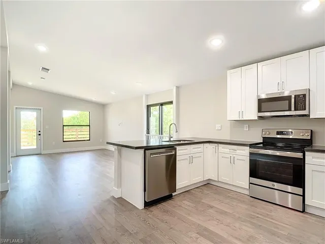 Kitchen with stainless steel appliances, a sink, dark countertops, visible vents, and a peninsula
