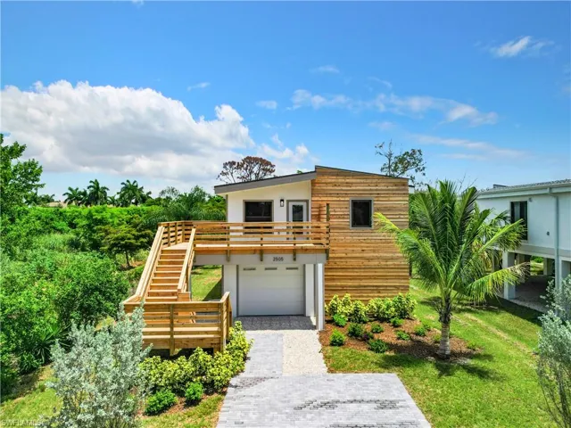 Contemporary house featuring stairway, stucco siding, an attached garage, a front lawn, and decorative driveway