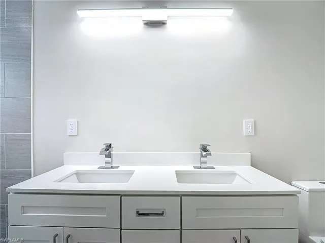 Full bath with toilet, a sink, and double vanity