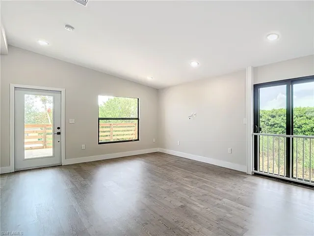 Unfurnished room featuring dark wood-style flooring, baseboards, and vaulted ceiling