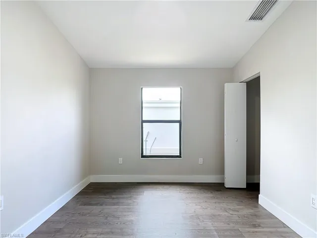 Spare room with wood finished floors, baseboards, and visible vents