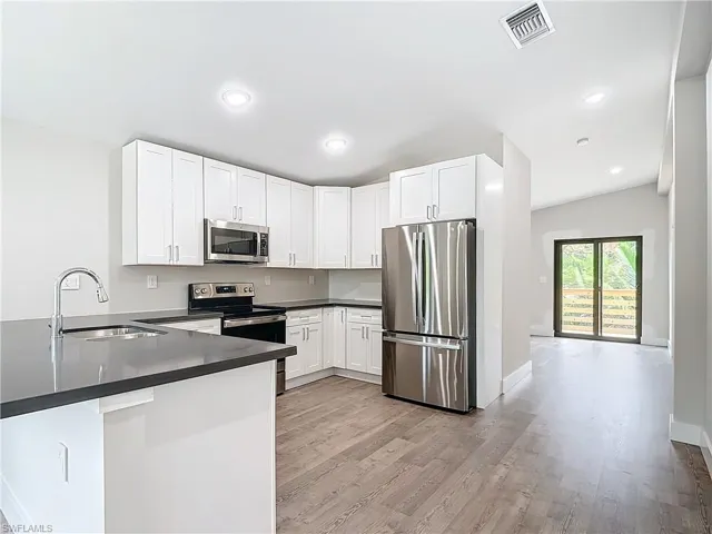 Kitchen featuring a sink, dark countertops, visible vents, a peninsula, and appliances with stainless steel finishes