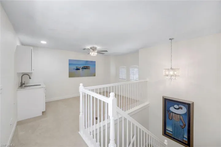 Hall with an upstairs landing, light colored carpet, and a chandelier