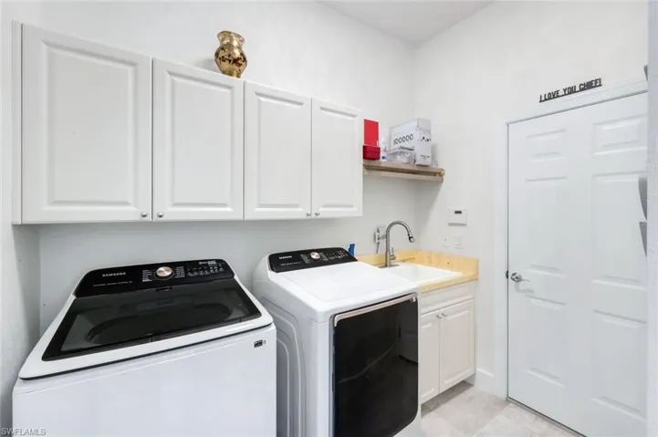 Washroom with cabinet space, washer and clothes dryer, and light tile patterned flooring