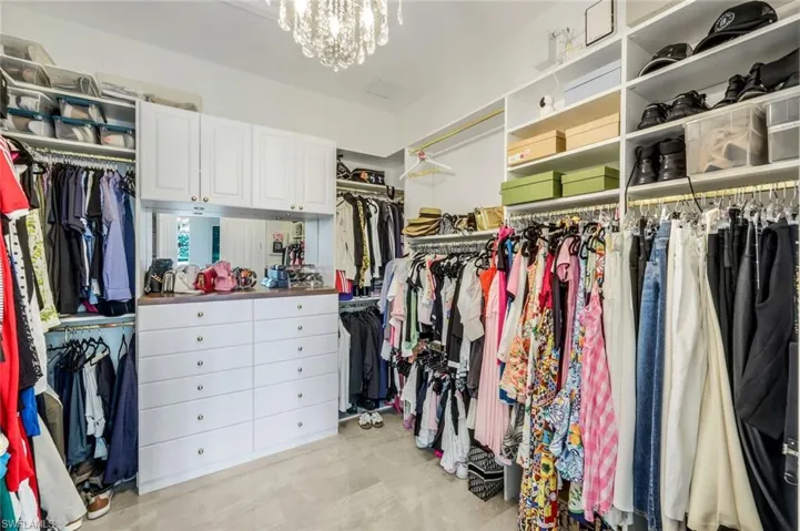 Spacious custom closet featuring a chandelier