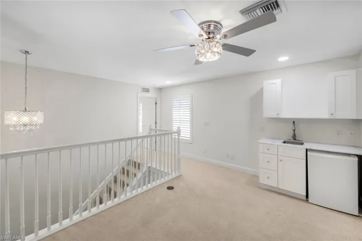 Bar with white dishwasher, white cabinetry, light countertops, light colored carpet, and recessed lighting