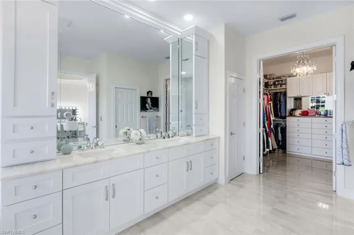Bathroom featuring double vanity, a chandelier, and a walk in closet