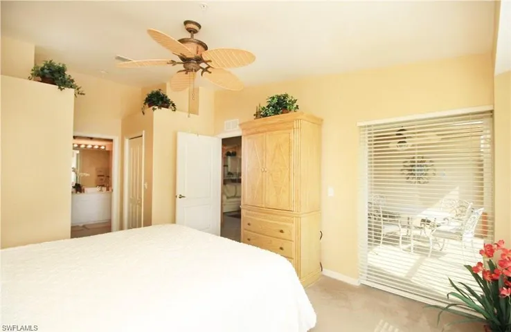 Carpeted bedroom with connected bathroom, access to exterior, ceiling fan, and a closet