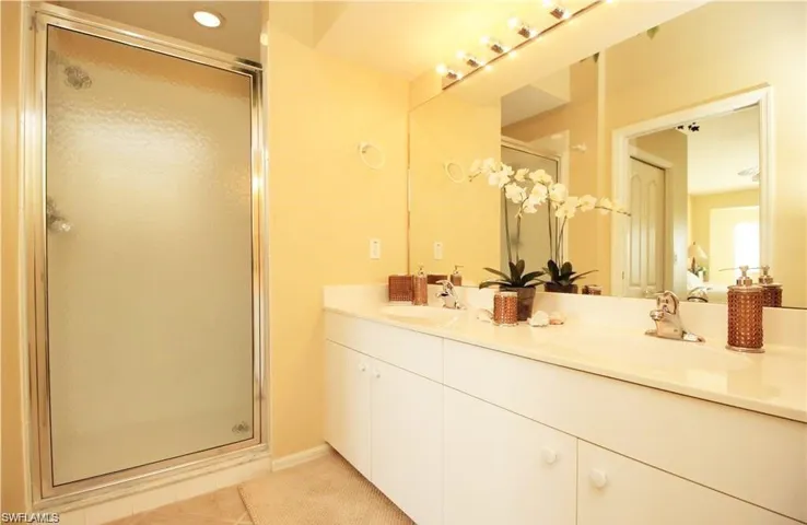 Bathroom featuring tile patterned floors, a shower with door, and vanity