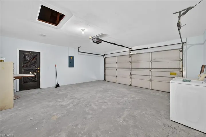 Garage featuring washer / clothes dryer, electric panel, and a garage door opener