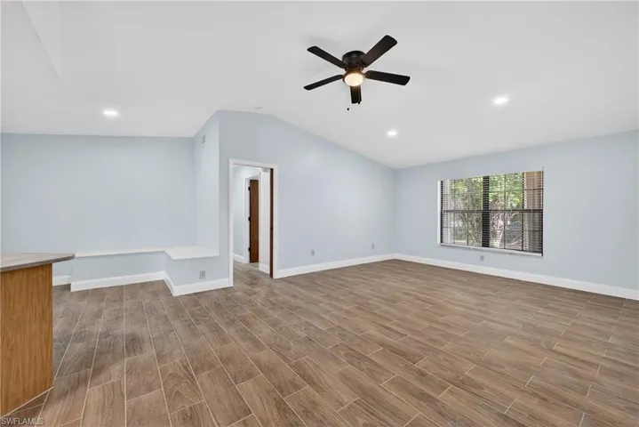 Unfurnished room with wood tiled floors, vaulted ceiling, ceiling fan, and recessed lighting