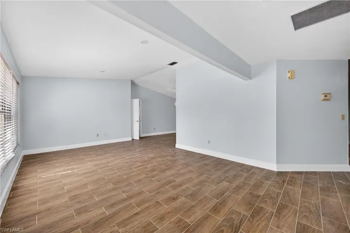 Unfurnished living room with wood tiled floors and lofted ceiling