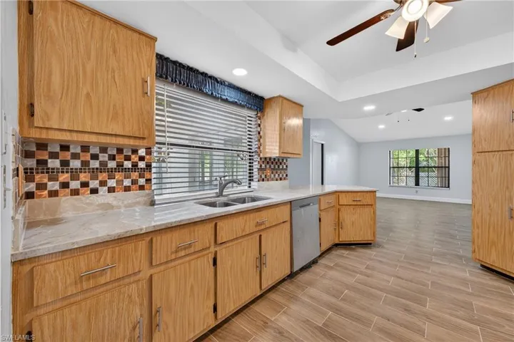 Kitchen featuring tasteful backsplash, light stone countertops, recessed lighting, a ceiling fan, and wood finish floors