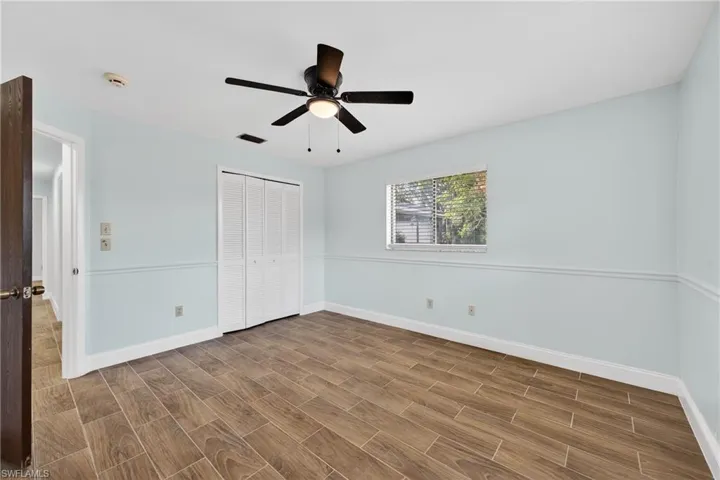 Unfurnished bedroom with wood tiled floors, a closet, and a ceiling fan