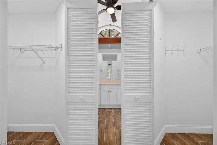 Walk in closet with wood finish floors and a ceiling fan
