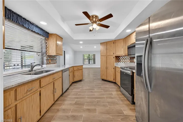 Kitchen featuring stainless steel appliances, recessed lighting, a peninsula, a ceiling fan, and wood finish floors