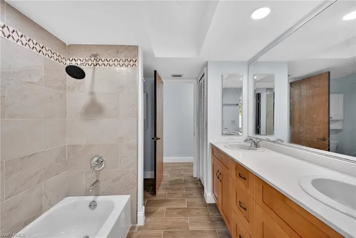 Full bathroom featuring double vanity, bathtub / shower combination, and wood tiled floors