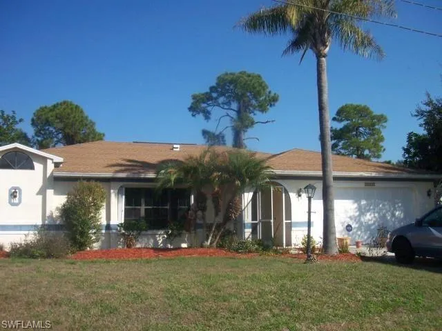 Ranch-style home featuring an attached garage, a front yard, and stucco siding