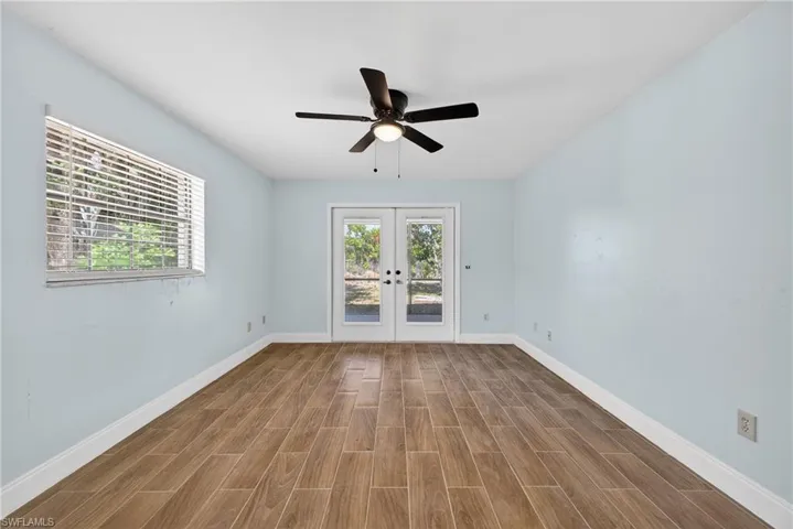 Empty room with french doors, wood finish floors, and ceiling fan