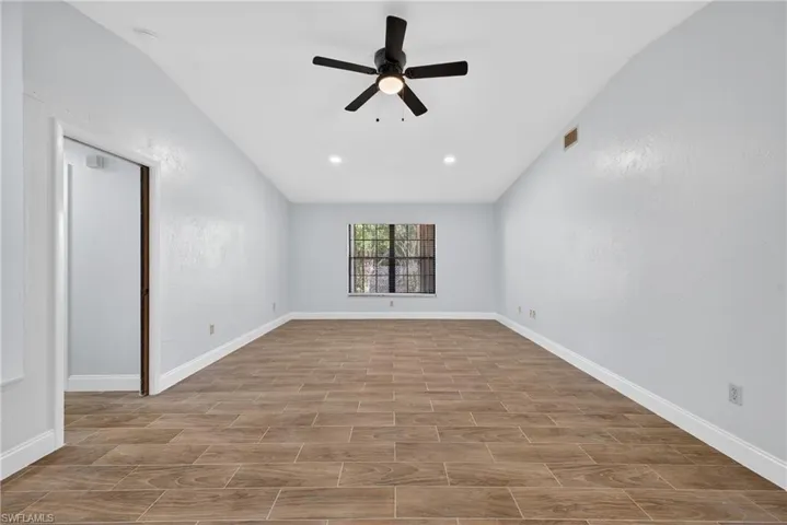 Spare room with a ceiling fan, wood tiled floors, and vaulted ceiling