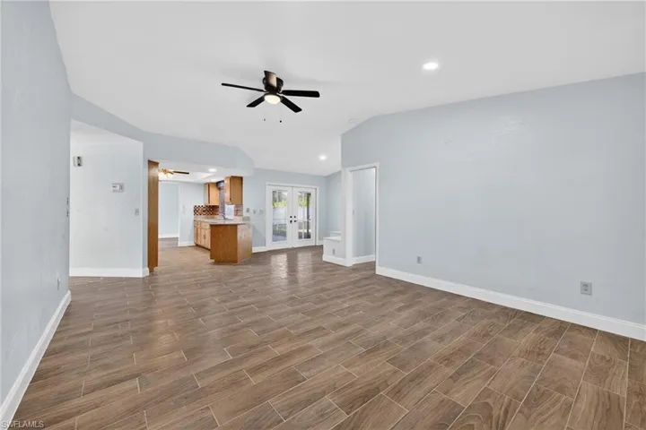 Unfurnished living room featuring a ceiling fan, wood tiled floors, recessed lighting, french doors, and lofted ceiling