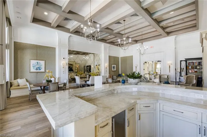 Kitchen featuring open floor plan, coffered ceiling, beamed ceiling, decorative light fixtures, and white cabinetry