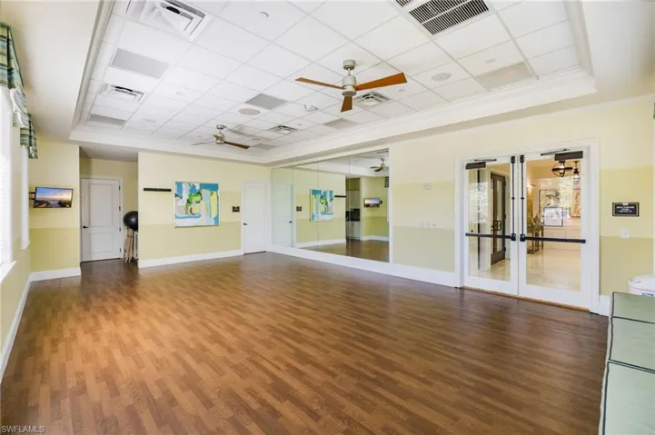 Exercise room with a paneled ceiling, french doors, and ceiling fan