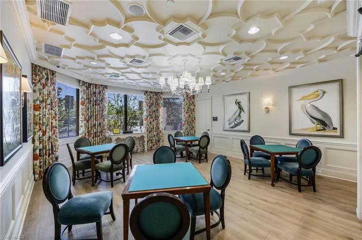Dining area with a decorative wall, wood finished floors, a chandelier, and ornamental molding