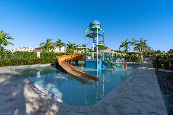 Community pool featuring a water slide, a water play area, and a patio area