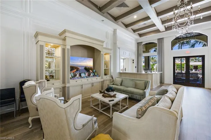 Living area featuring french doors, beamed ceiling, a towering ceiling, wood finished floors, and coffered ceiling