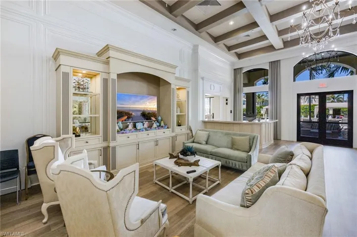 Living area featuring beam ceiling, wood finished floors, a towering ceiling, coffered ceiling, and french doors